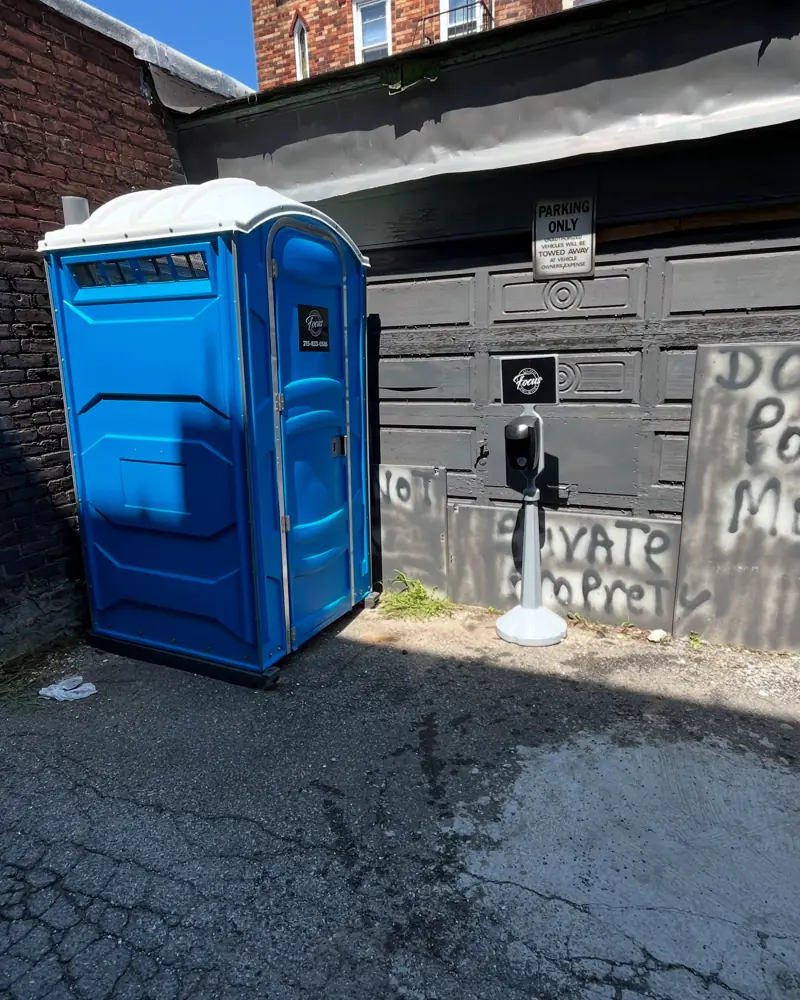 Blue standard porta potty placed in a narrow commercial alley