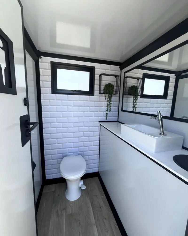 Tiled restroom trailer interior with toilet and long vanity counter