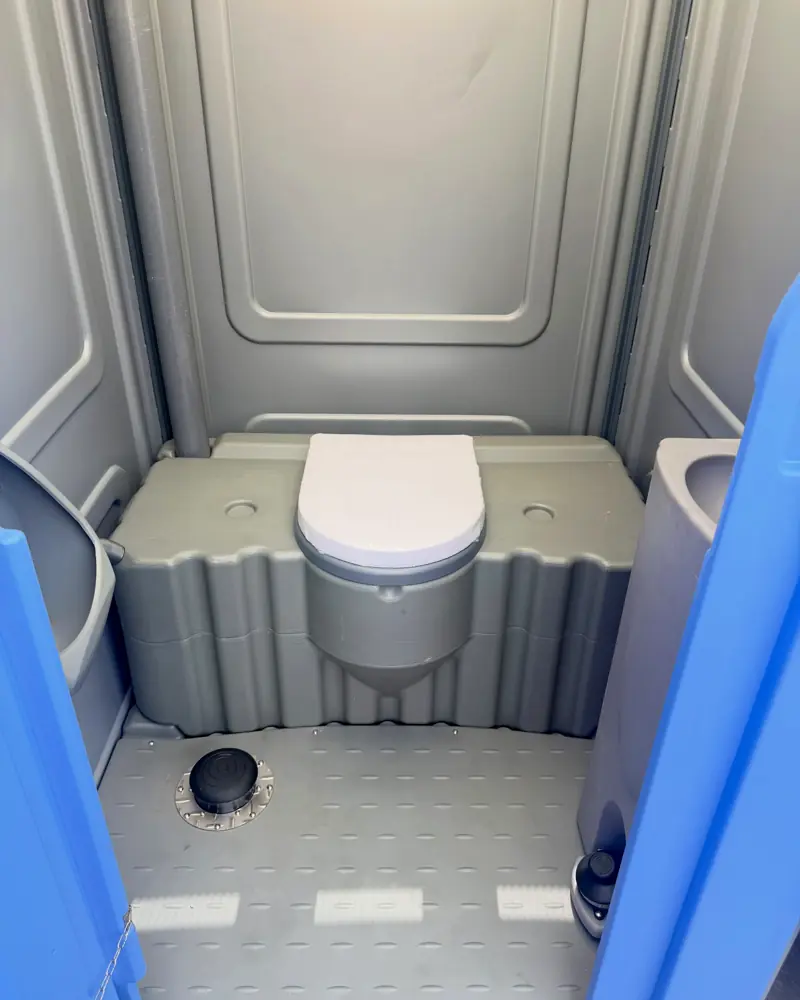 Grey standard porta potty interior with molded seat and anti-slip floor